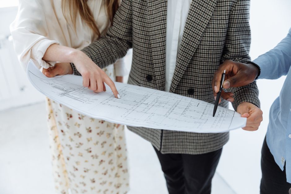 Adults reviewing detailed schematic floor plans indoors for a new building.